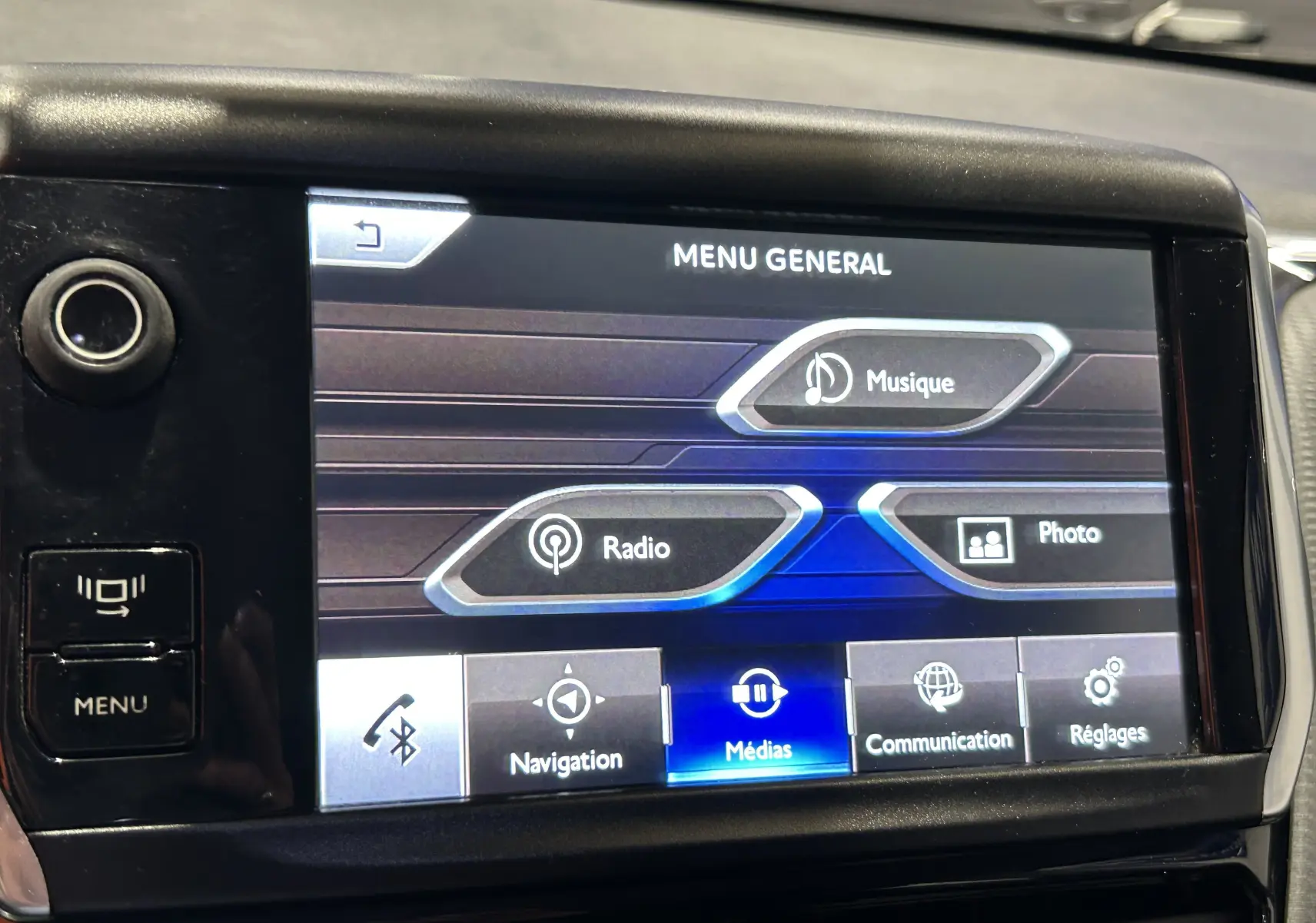 Écran tactile central de la Peugeot 2008 blanc, affichant le menu général multimédia avec options Musique, Radio et Photo.