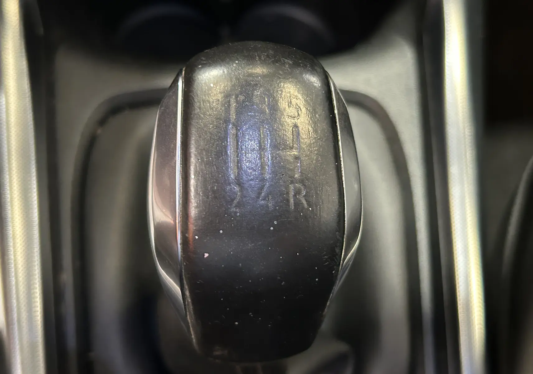 Gros plan sur le levier de vitesses noir de la Peugeot 2008 VTi 82 Allure, boîte manuelle, intérieur sombre.