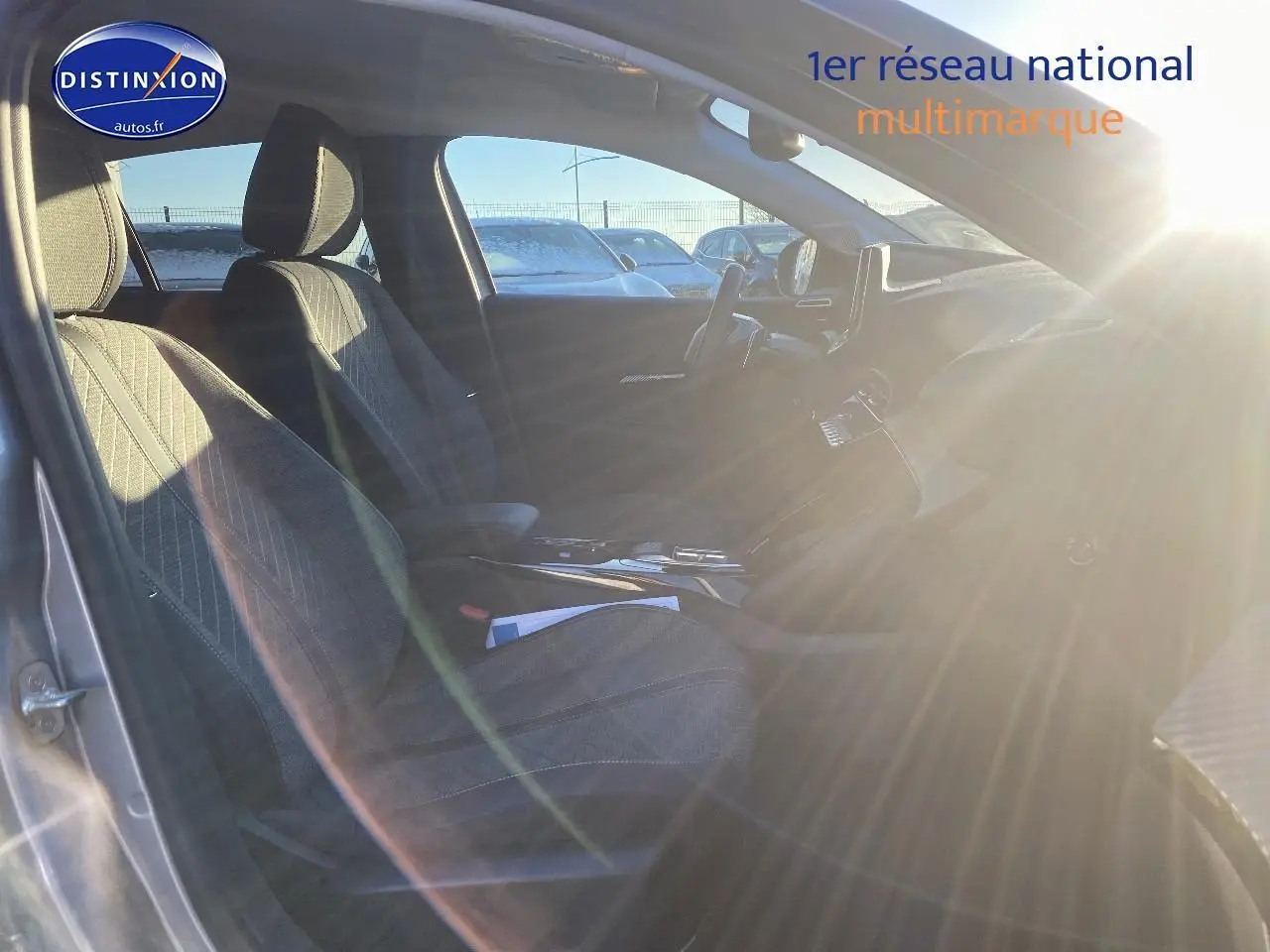 Intérieur avant droit de la Peugeot 208 gris artense 2025, sièges tissu avec accoudoir central et tableau de bord moderne.