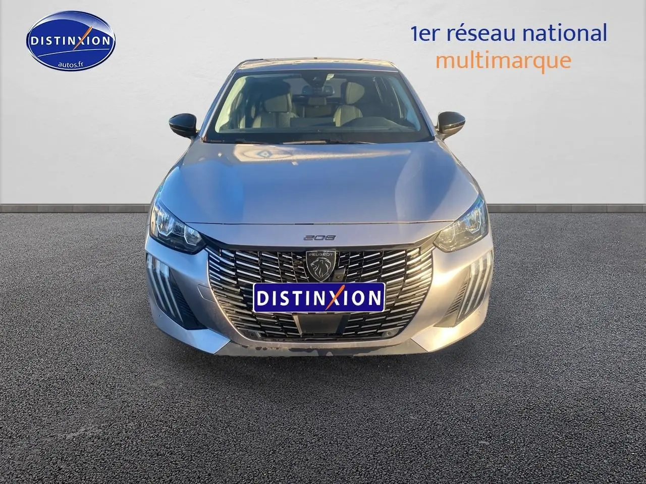 Vue frontale d'une Peugeot 208 gris artense avec calandre noire et phares LED allumés.