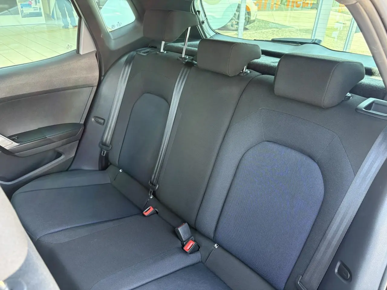 Vue intérieure côté gauche de la banquette arrière noire en textile du SEAT Arona 2024 avec appuie-têtes et ceintures de sécurité.