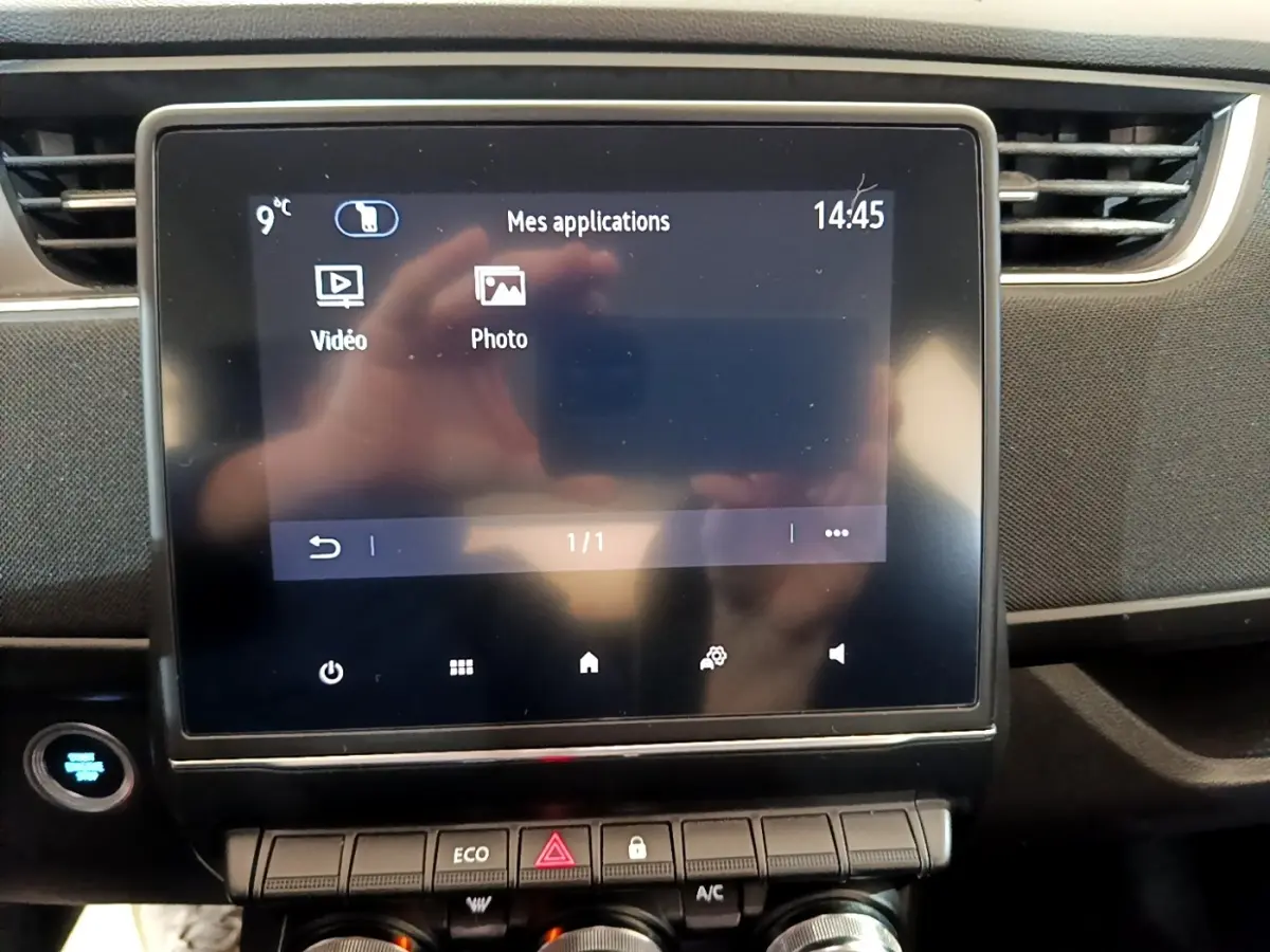 Écran tactile central de la Renault ZOE Business R110 2021, affichant les applications vidéo et photo, avec tableau de bord noir.