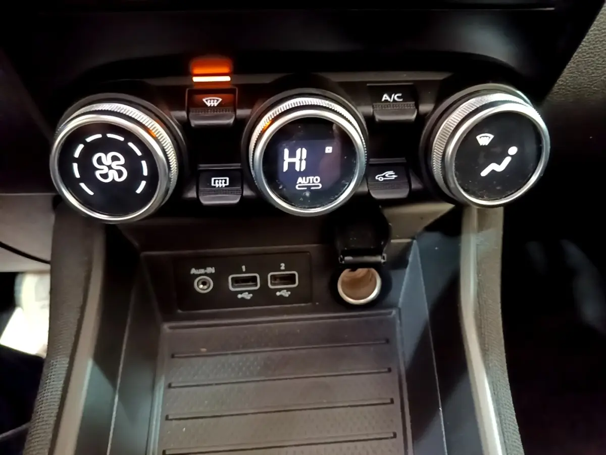 Gros plan sur les commandes de climatisation et les ports USB d'une Renault ZOE Business R110 blanche de 2021.