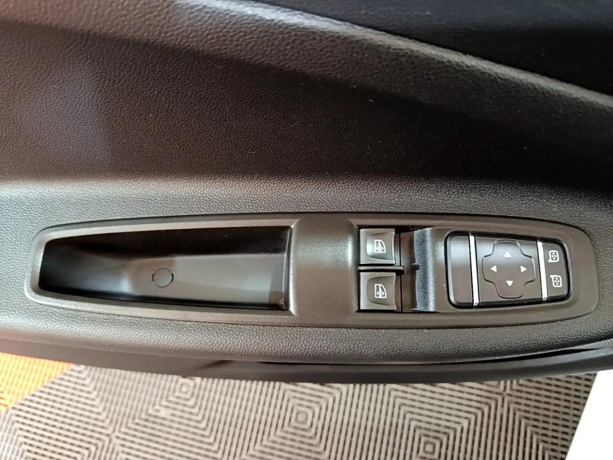 Vue rapprochée des commandes de lève-vitres et réglage des rétroviseurs sur la porte côté conducteur d'une Renault ZOE blanche.