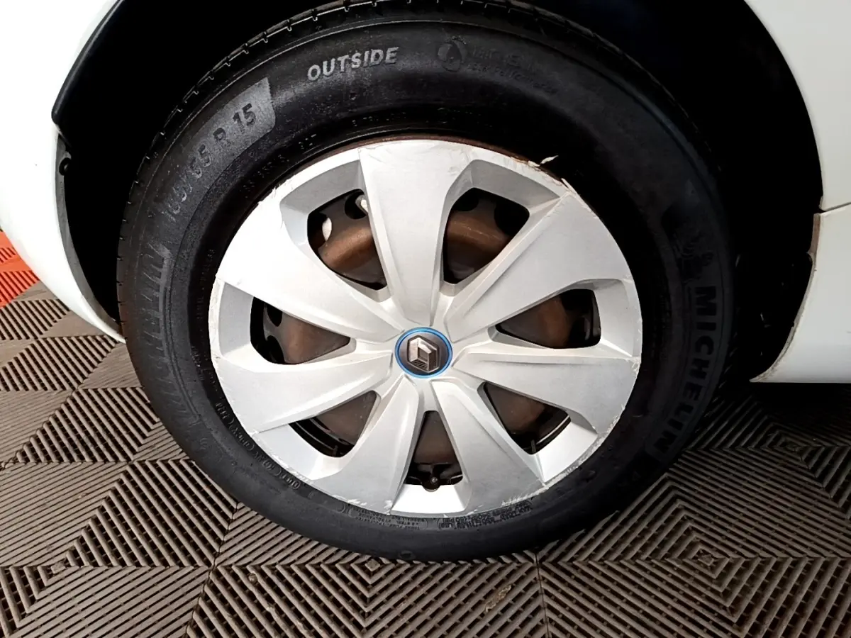 Gros plan sur la roue avant droite blanche d'une Renault ZOE Business R110 2021 avec jante en plastique et logo Renault.