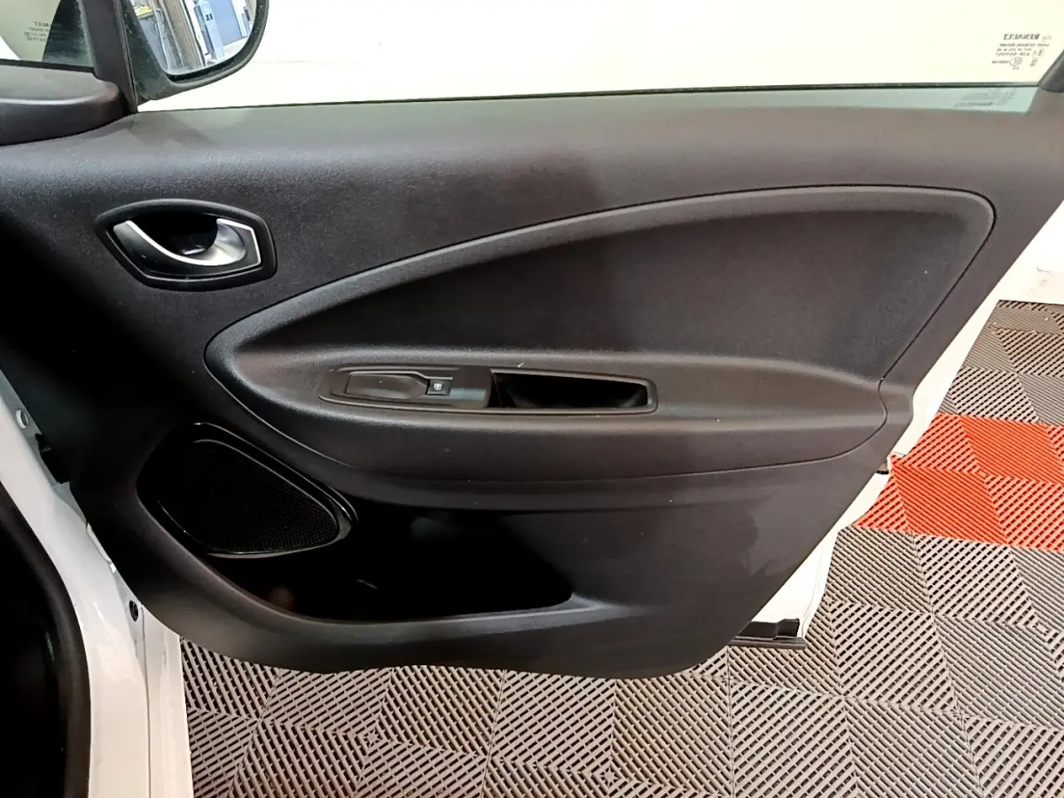 Vue intérieure côté gauche de la porte avant blanche de la Renault ZOE Business R110 avec commande de fenêtre et haut-parleur intégré.
