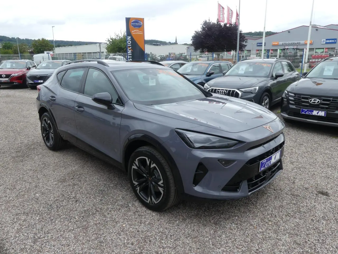 Vue 3/4 avant du CUPRA Formentor gris Graphène avec coques de rétroviseurs noires sur parking extérieur.