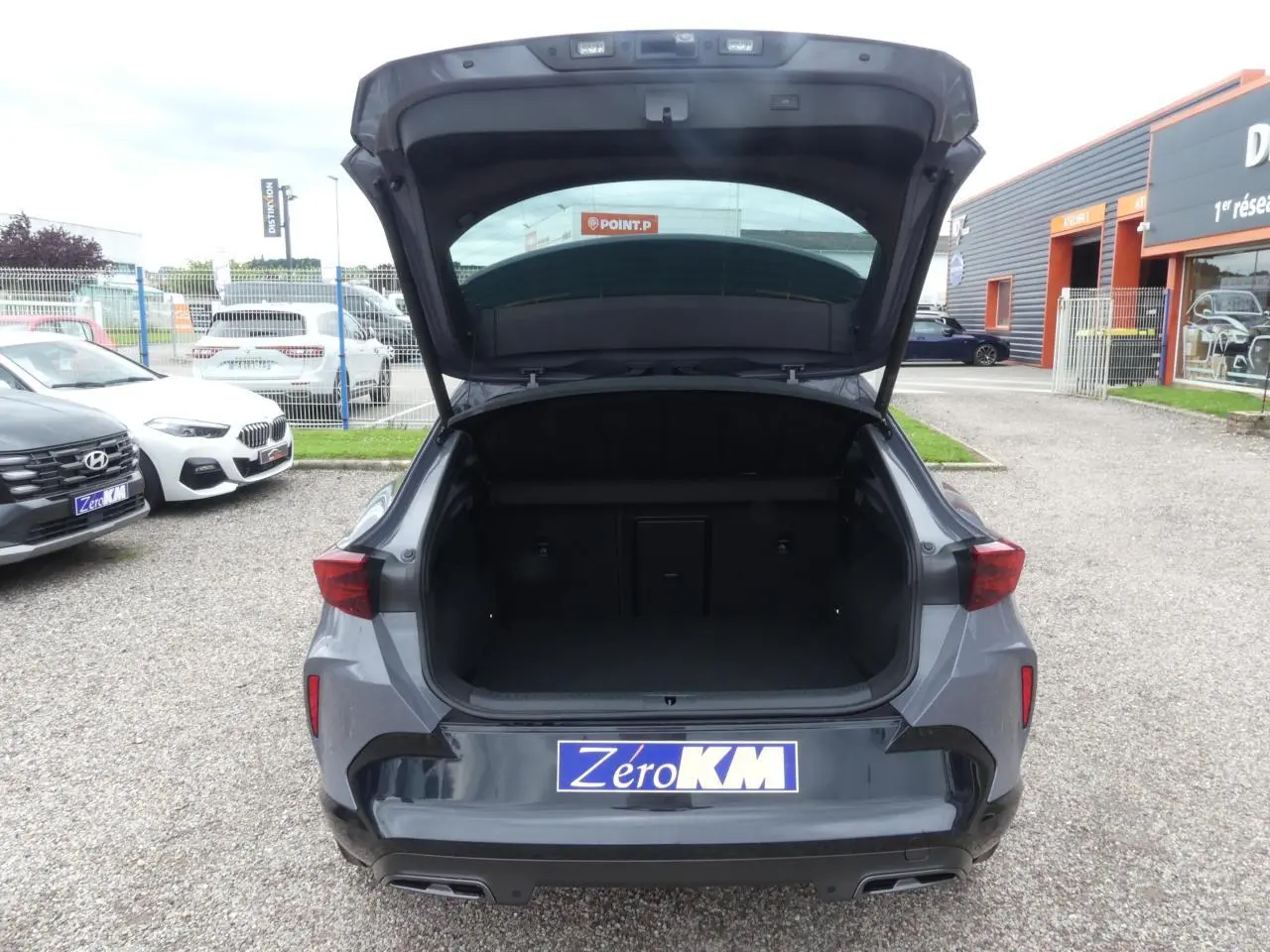 Vue arrière ouverte du CUPRA Formentor gris Graphène avec coffre spacieux et feux arrière triangulaires allumés.