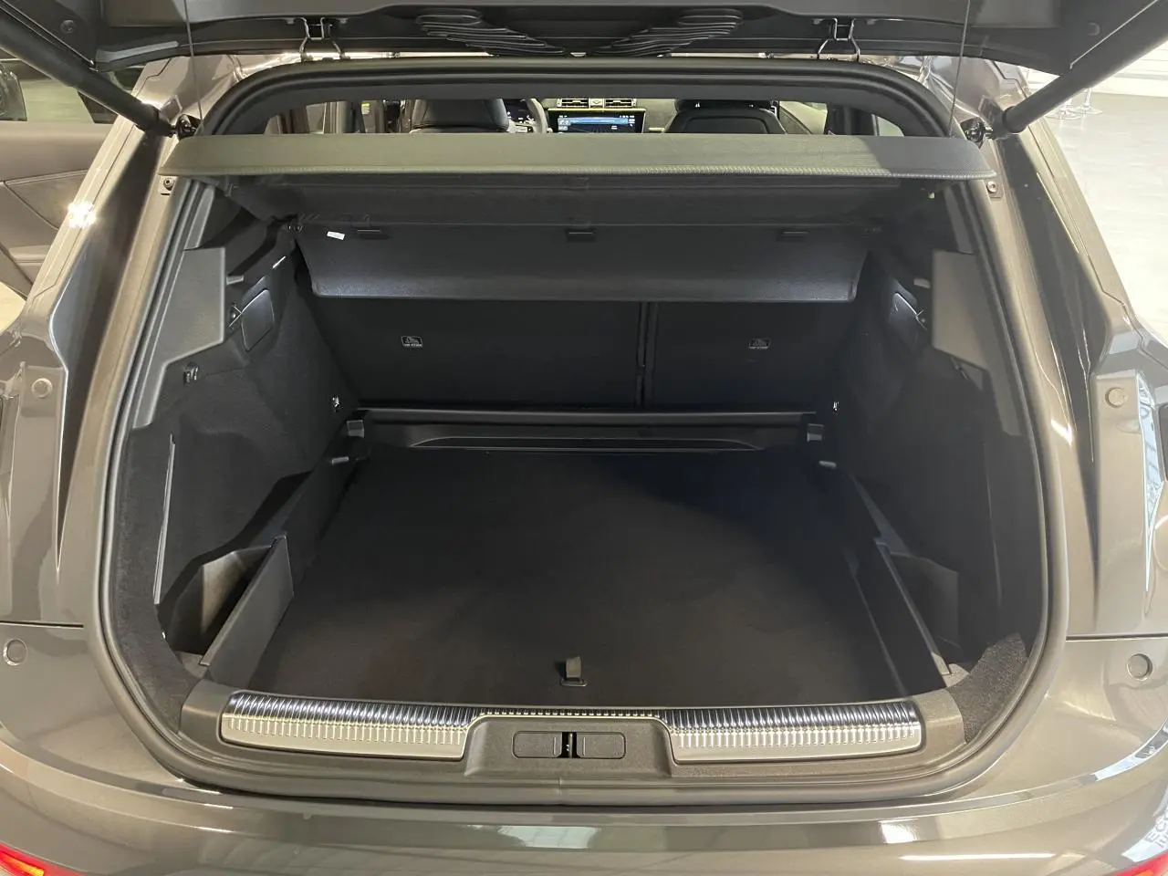 Vue arrière du coffre ouvert du DS7 Crossback gris titanium avec seuil de coffre chromé et habillage intérieur noir.