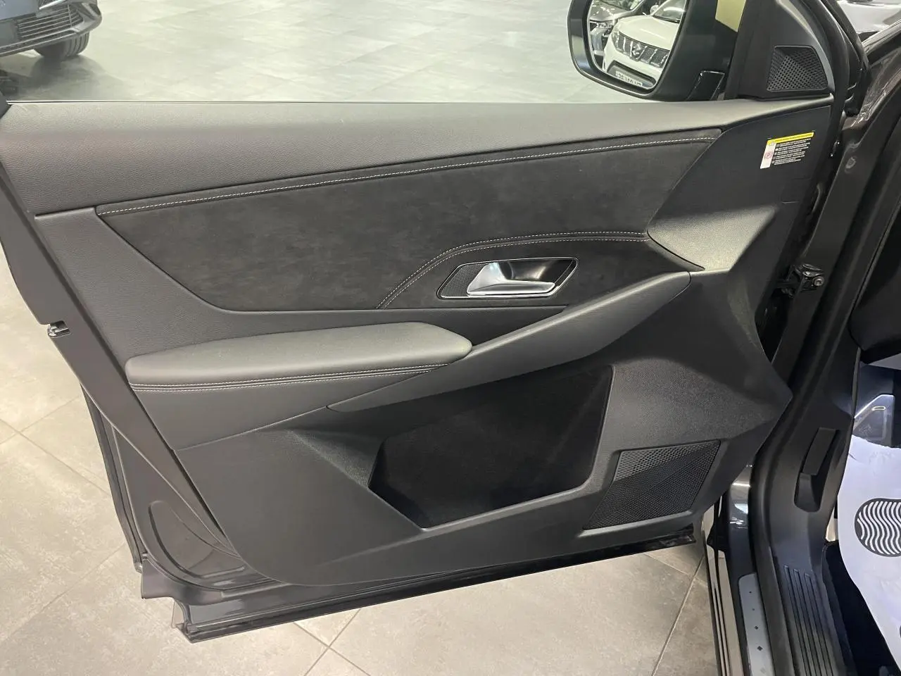Vue intérieure de la porte avant gauche du DS7 Crossback gris titanium avec habillage Alcantara noir et surpiqûres contrastées.