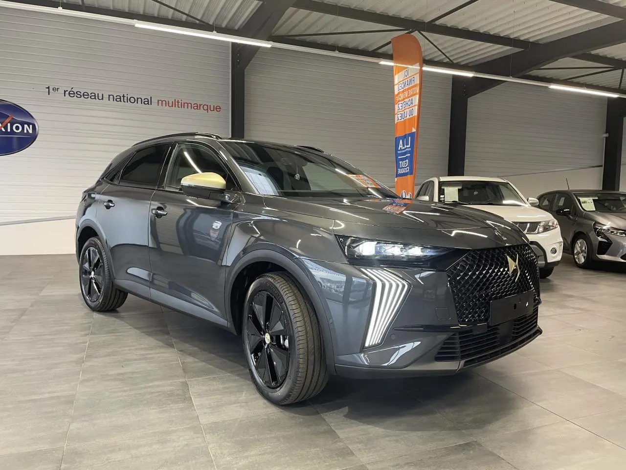 DS7 Crossback gris titanium en 3/4 avant droit, avec calandre noire et coques de rétroviseurs dorées satinées.
