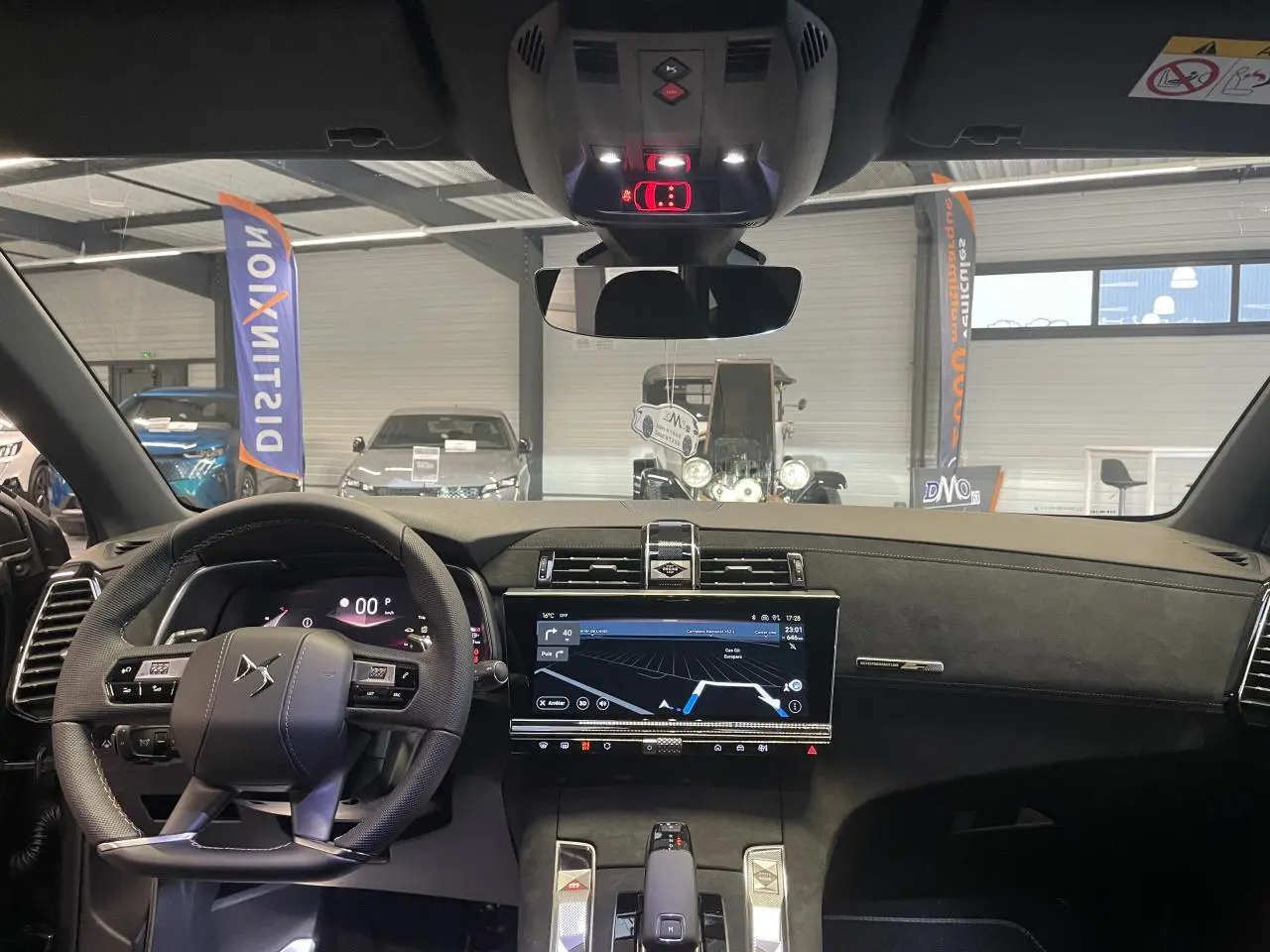 Vue intérieure avant du DS7 Crossback gris titanium, mettant en valeur le volant cuir perforé et l'écran tactile central.