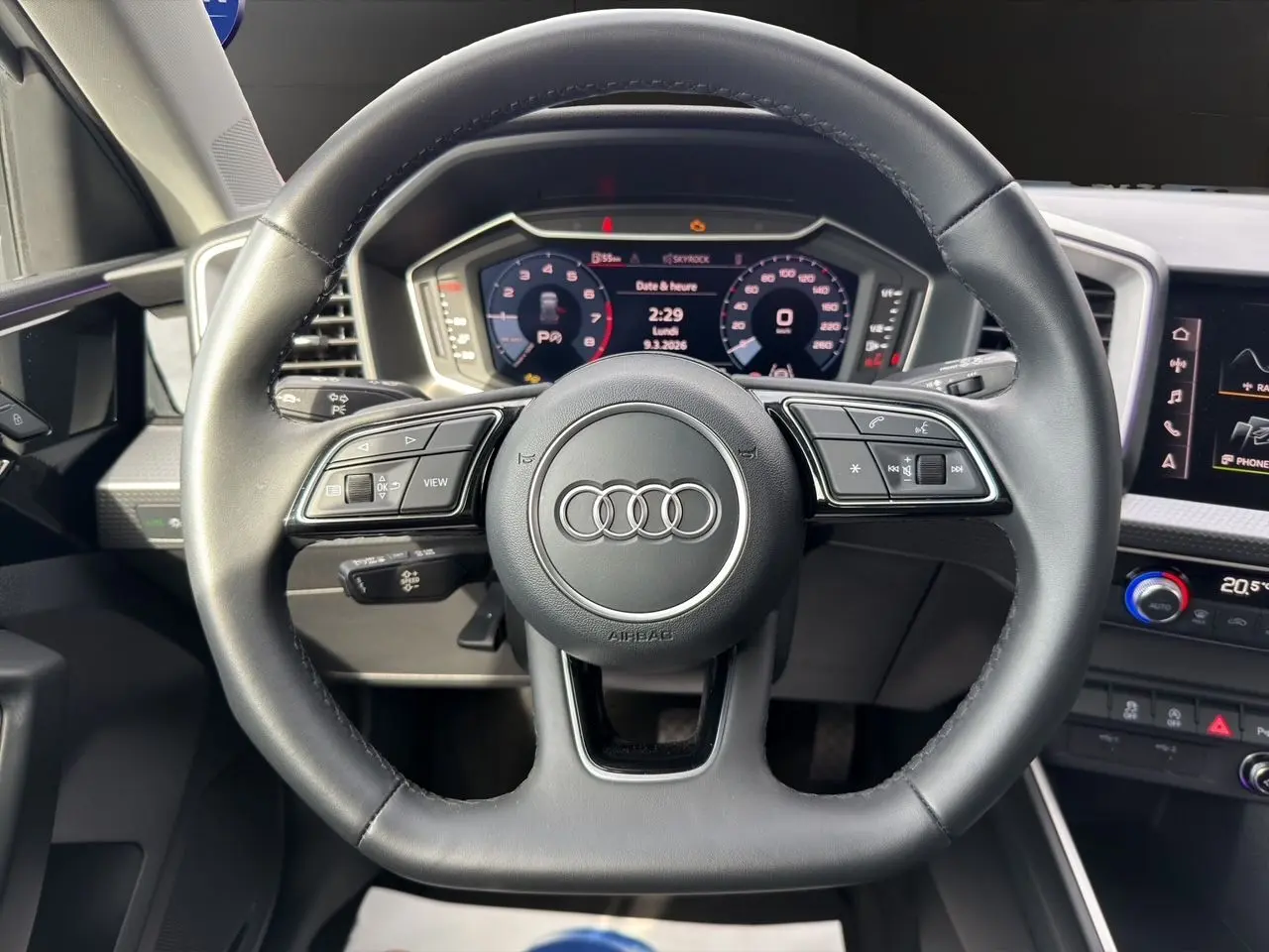 Vue intérieure centrée sur le volant cuir noir multifonction de l'Audi A1 Sportback avec tableau de bord numérique.