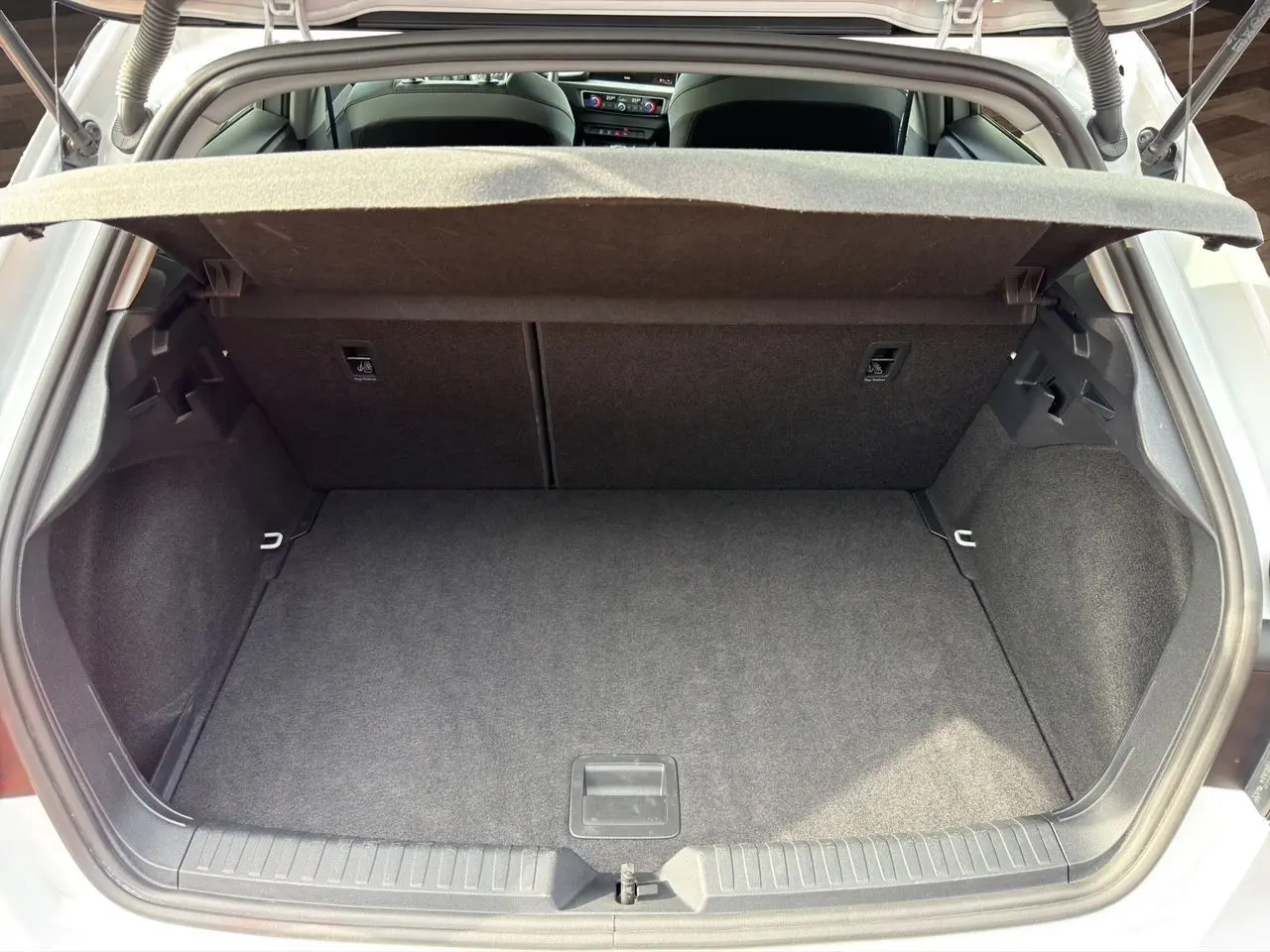 Coffre ouvert vu de l'arrière d'une Audi A1 Sportback blanche avec intérieur noir et cache-bagages déployé.