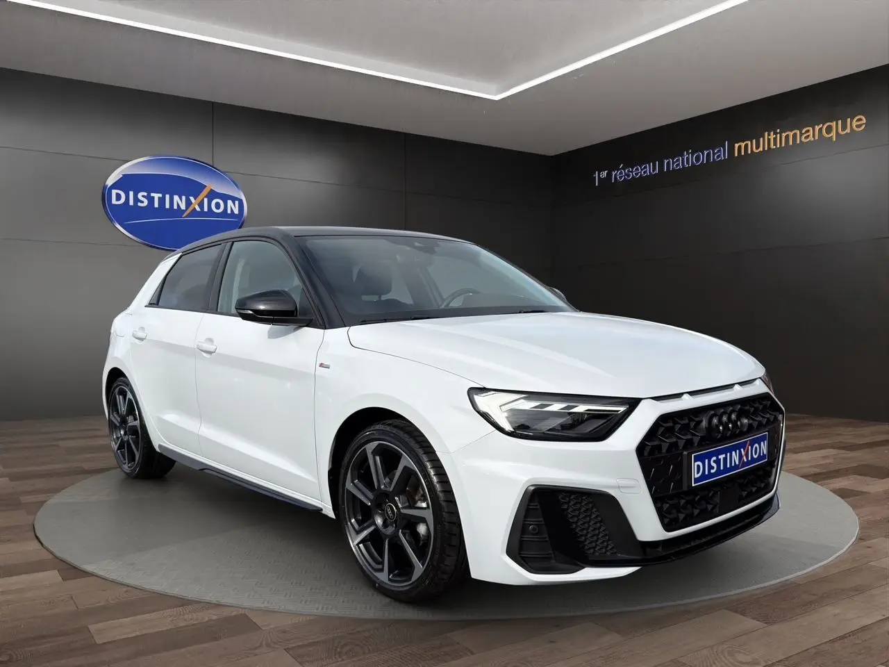Audi A1 Sportback blanc à toit noir en 3/4 avant droit, avec jantes 18 pouces noires et calandre noire distinctive.