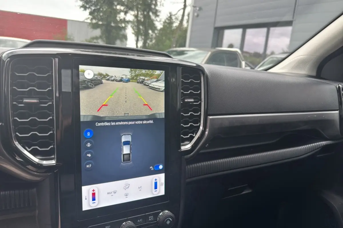 Vue intérieure du tableau de bord du Ford Ranger 2026 avec écran tactile affichant la caméra de recul et les commandes climatisation.