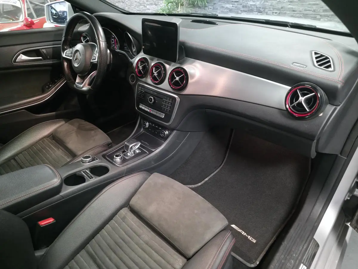 Intérieur avant droit de la Mercedes CLA Shooting Brake gris, avec aérateurs AMG cerclés de rouge et sellerie noire.