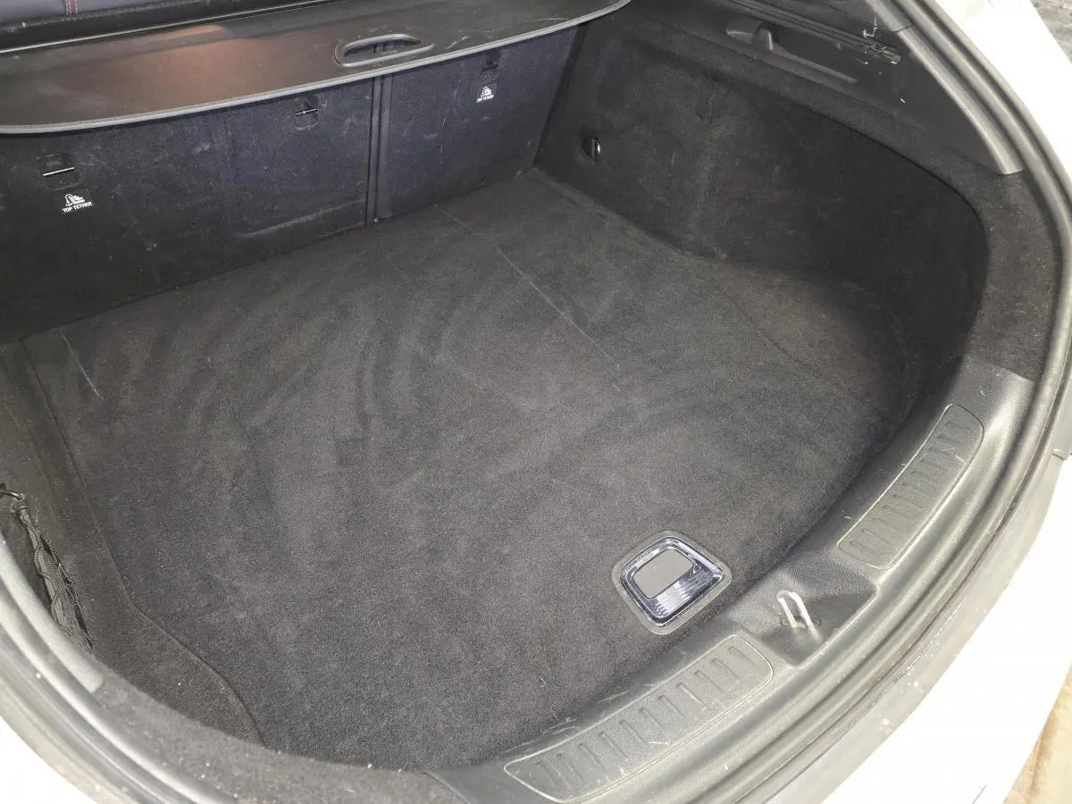 Coffre ouvert d'une Mercedes Classe CLA Shooting Brake gris, vue plongeante sur l'espace de chargement vide.