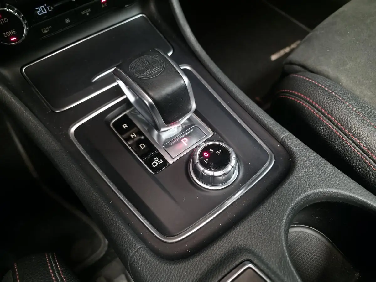 Gros plan sur la console centrale noire avec levier de vitesse automatique et sélecteur de modes AMG rouge et noir.