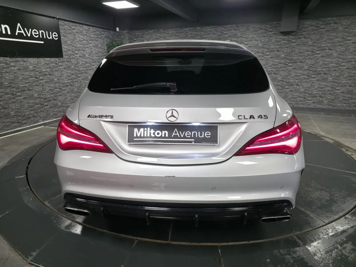 Vue arrière d'une Mercedes CLA 45 AMG gris métallisé avec feux LED allumés et double sortie d'échappement chromée.