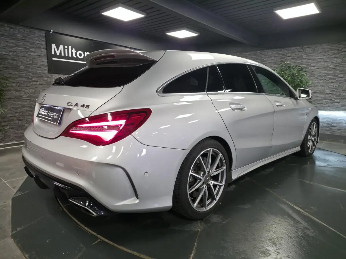 Mercedes CLA 45 Shooting Brake gris vue 3/4 arrière droit, feux arrière allumés et jantes AMG 18 pouces visibles.