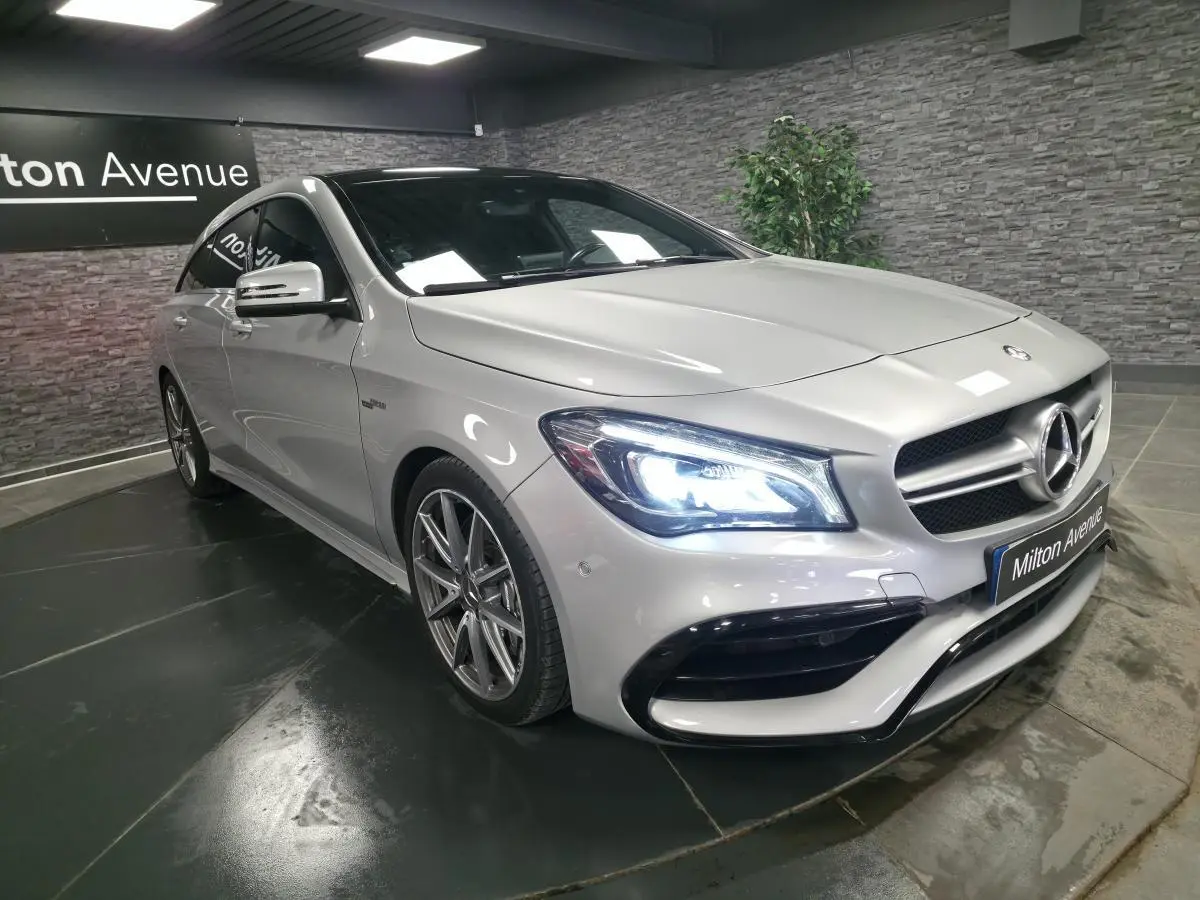 Mercedes CLA Shooting Brake gris, vue 3/4 avant droit avec phares LED allumés et jantes AMG 18 pouces.