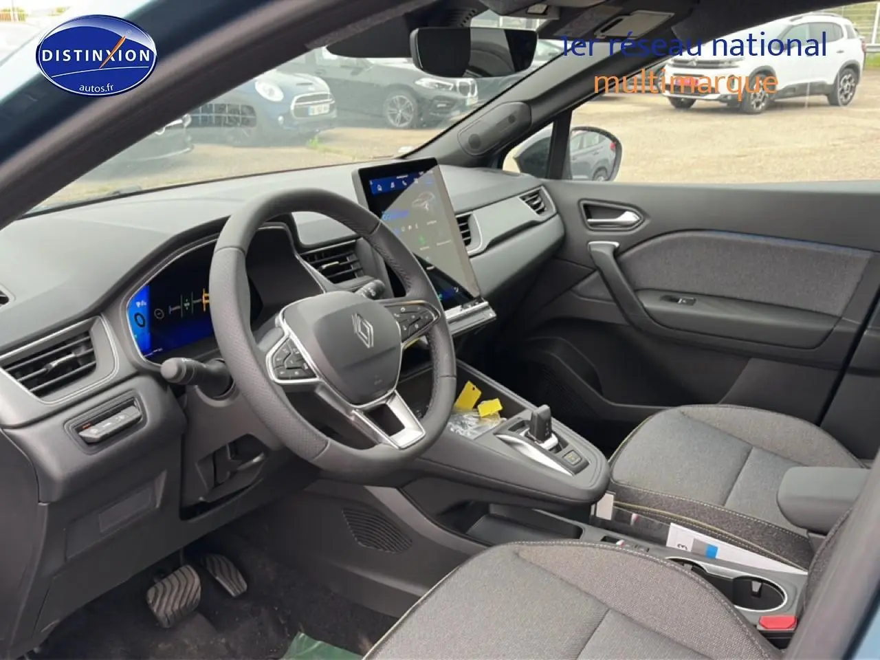 Vue intérieure côté conducteur de la Renault Symbioz 2026, tableau de bord moderne avec écran tactile vertical et sellerie textile grise.