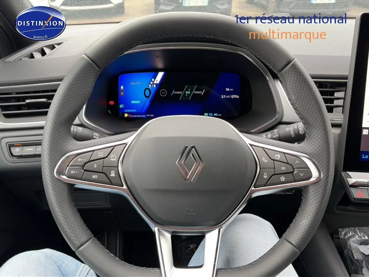 Vue intérieure centrée sur le volant noir perforé avec logo Renault et tableau de bord numérique bleu du Symbioz 2026.