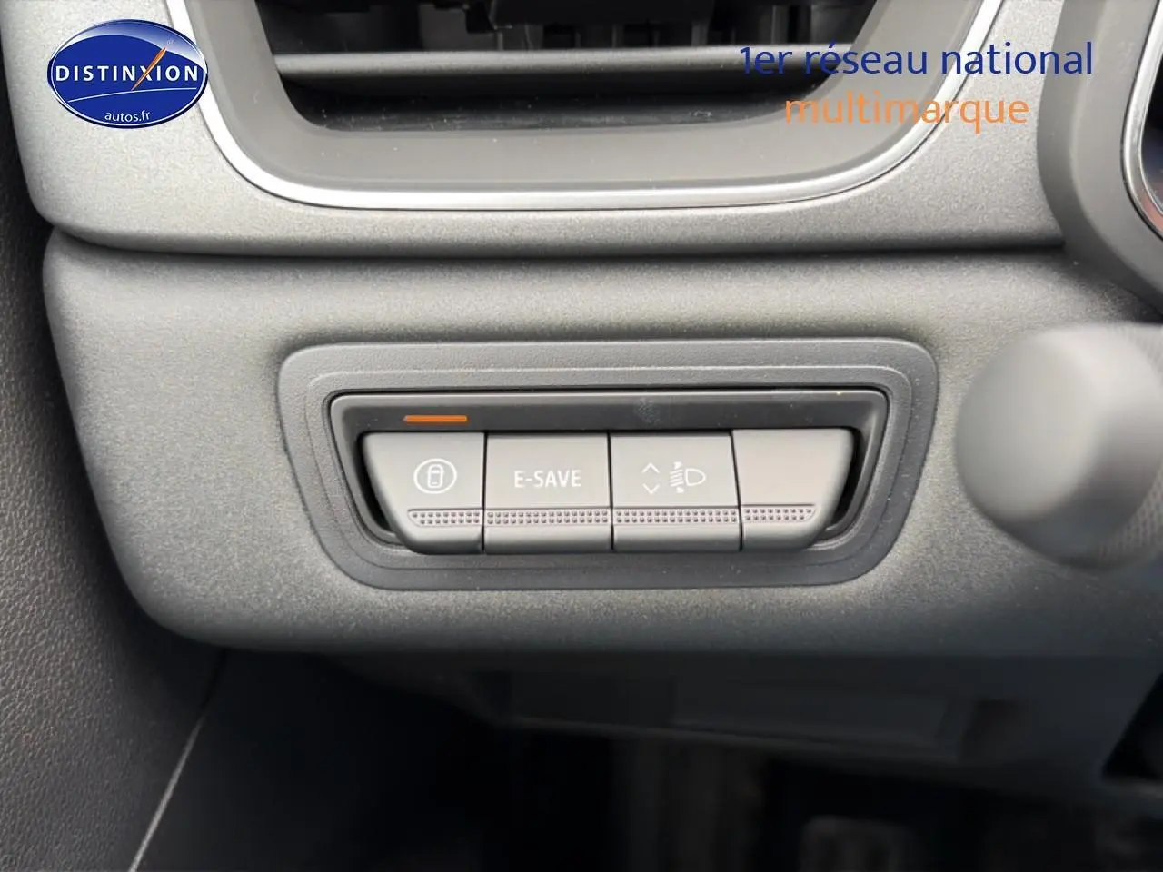 Gros plan sur les boutons de commande E-SAVE et réglage des phares dans l'habitacle de la Renault Symbioz bleu mercure.