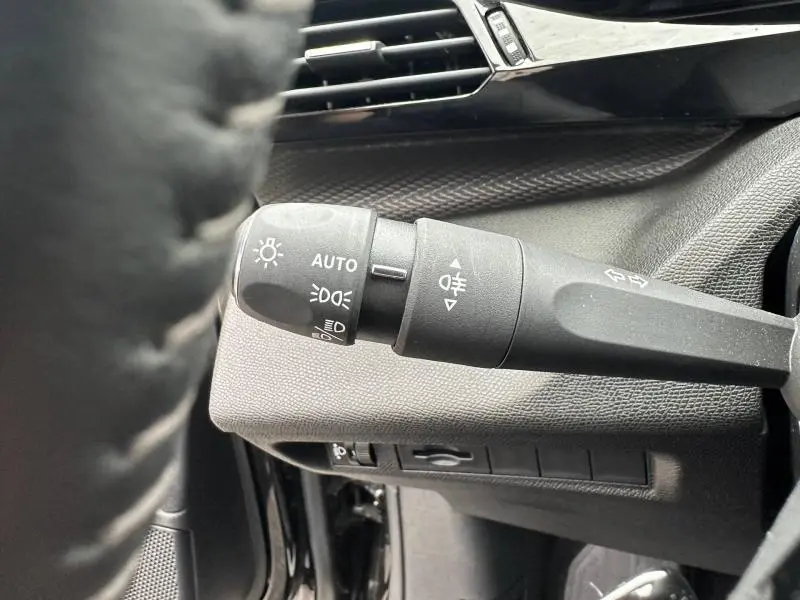 Gros plan sur la commande des feux du tableau de bord d'une Peugeot 308 2024 noir Perla Nera, intérieur noir.