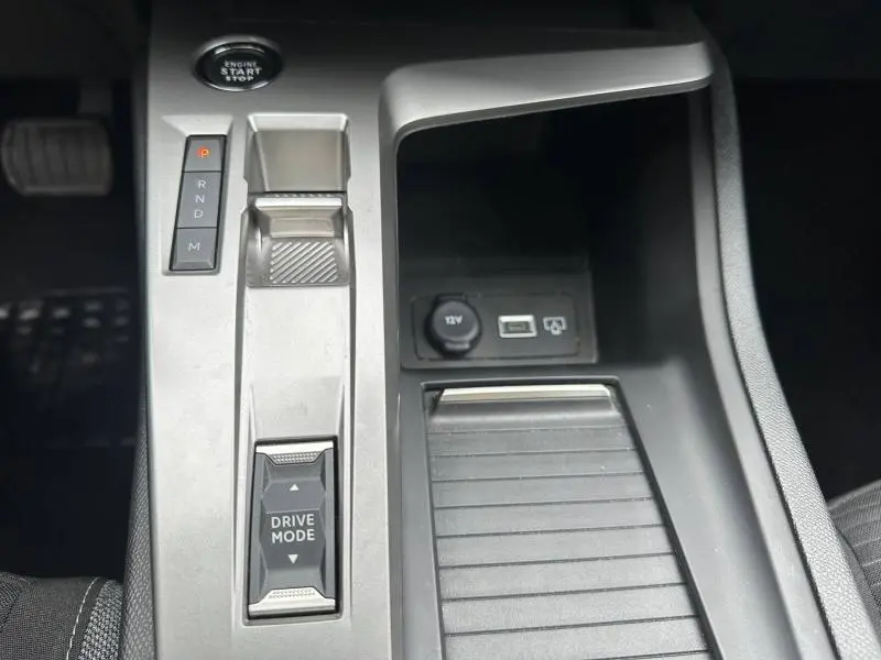 Vue rapprochée de la console centrale de la Peugeot 308 2024, avec commandes boîte auto, bouton Drive Mode et prise 12V.