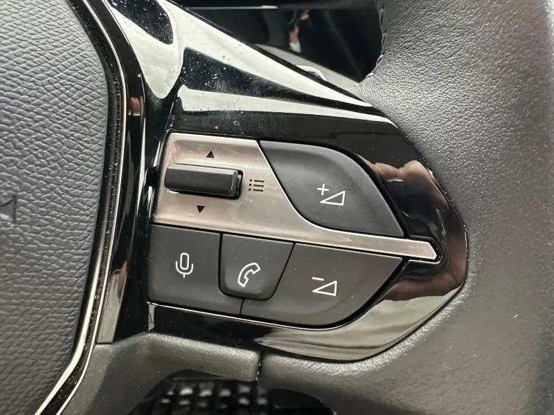 Gros plan sur les commandes audio et téléphone au volant côté gauche du Peugeot 308 noir Perla Nera 2024.