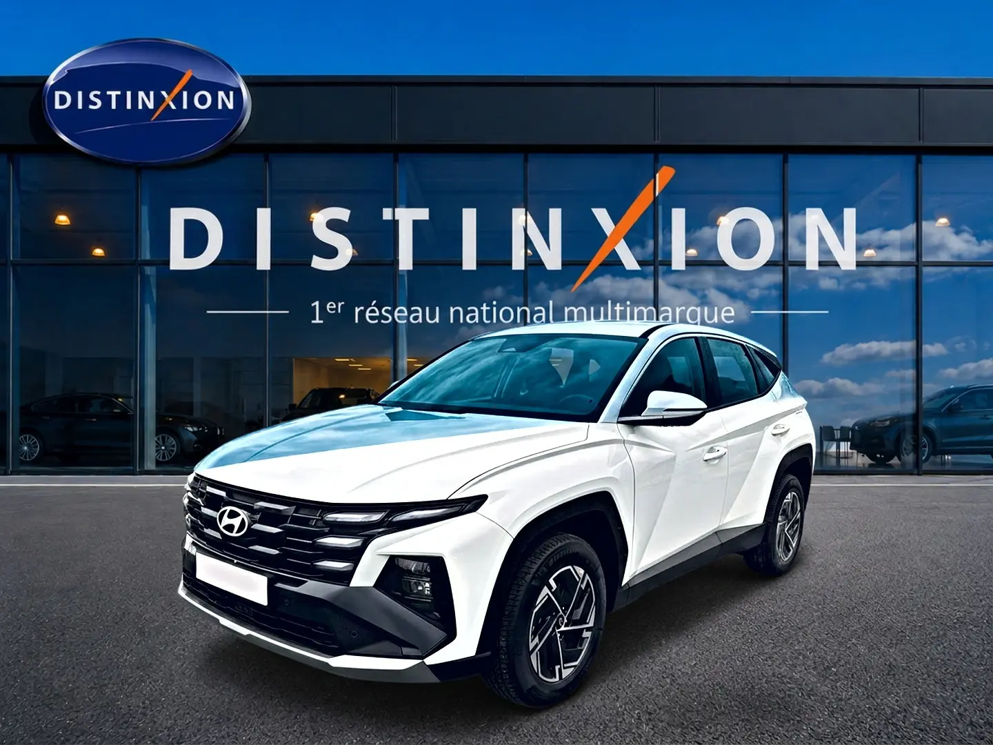 Hyundai Tucson blanc 2026 en 3/4 avant droit, avec calandre noire et jantes alliage 17 pouces visibles.