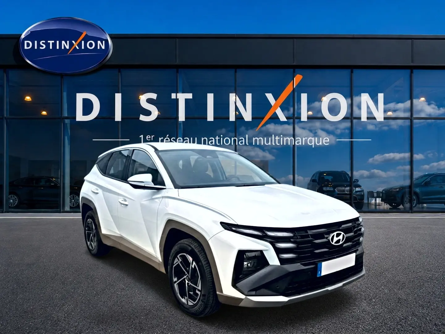 Hyundai Tucson blanc en 3/4 avant droit, avec calandre noire et jantes alliage 17 pouces devant showroom Distinxion.