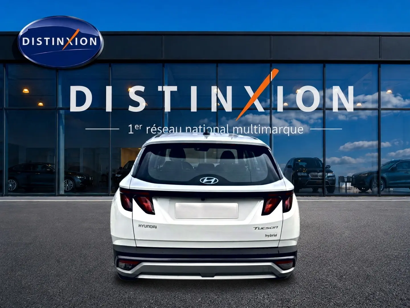 Vue arrière d'un Hyundai Tucson blanc hybride 2026, avec feux arrière sombres et logo Hyundai visible.