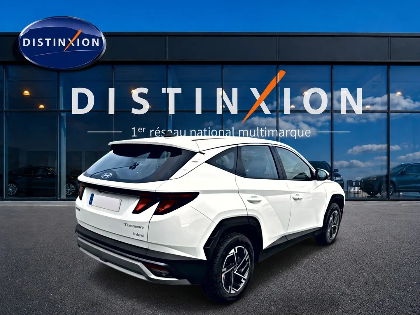 Vue 3/4 arrière droite d'un Hyundai Tucson blanc hybride 2026 avec jantes alliage et feux arrière LED distinctifs.