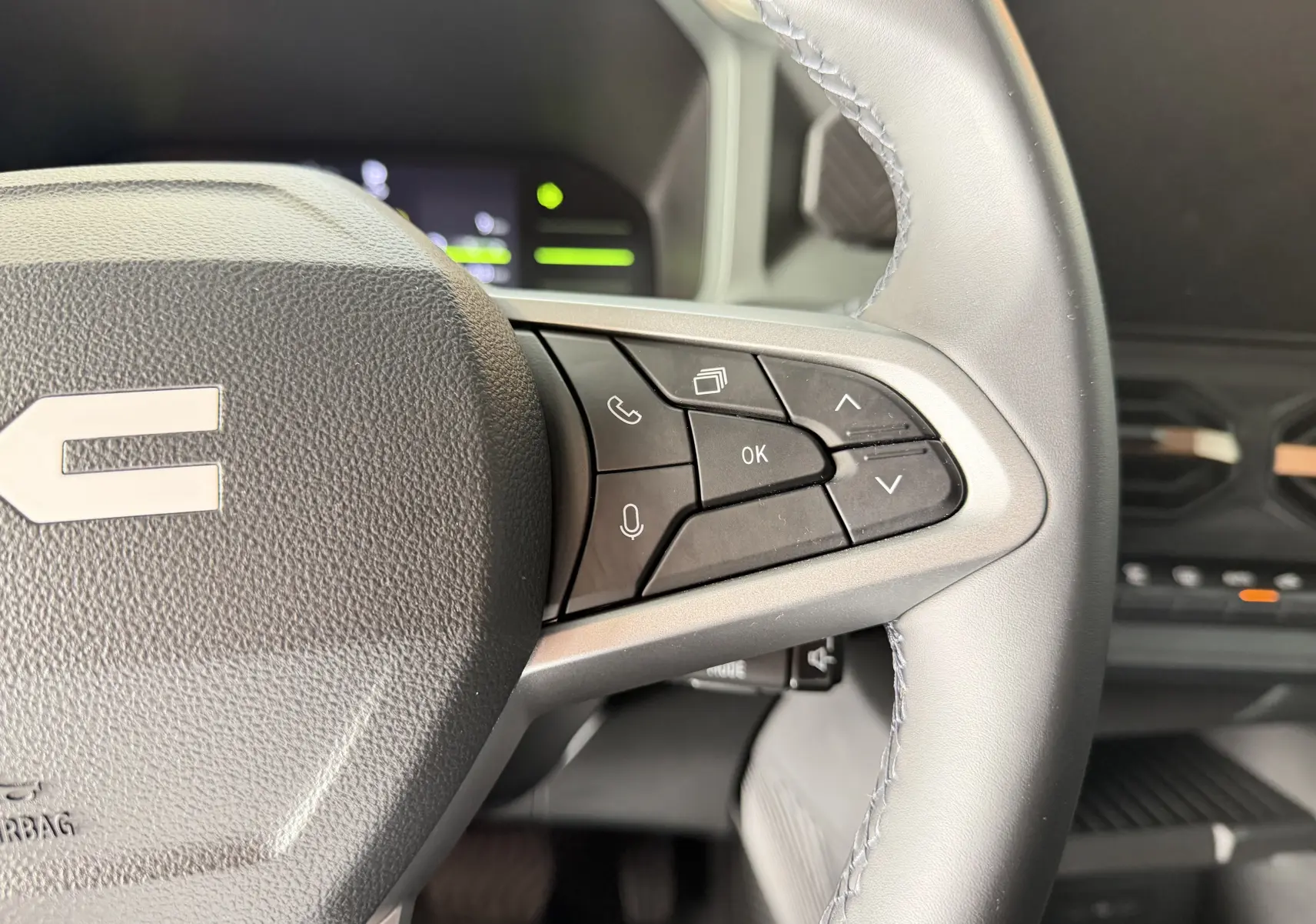 Gros plan sur les commandes multifonctions à droite du volant du Dacia Duster Hybrid 155 Extreme, intérieur noir.