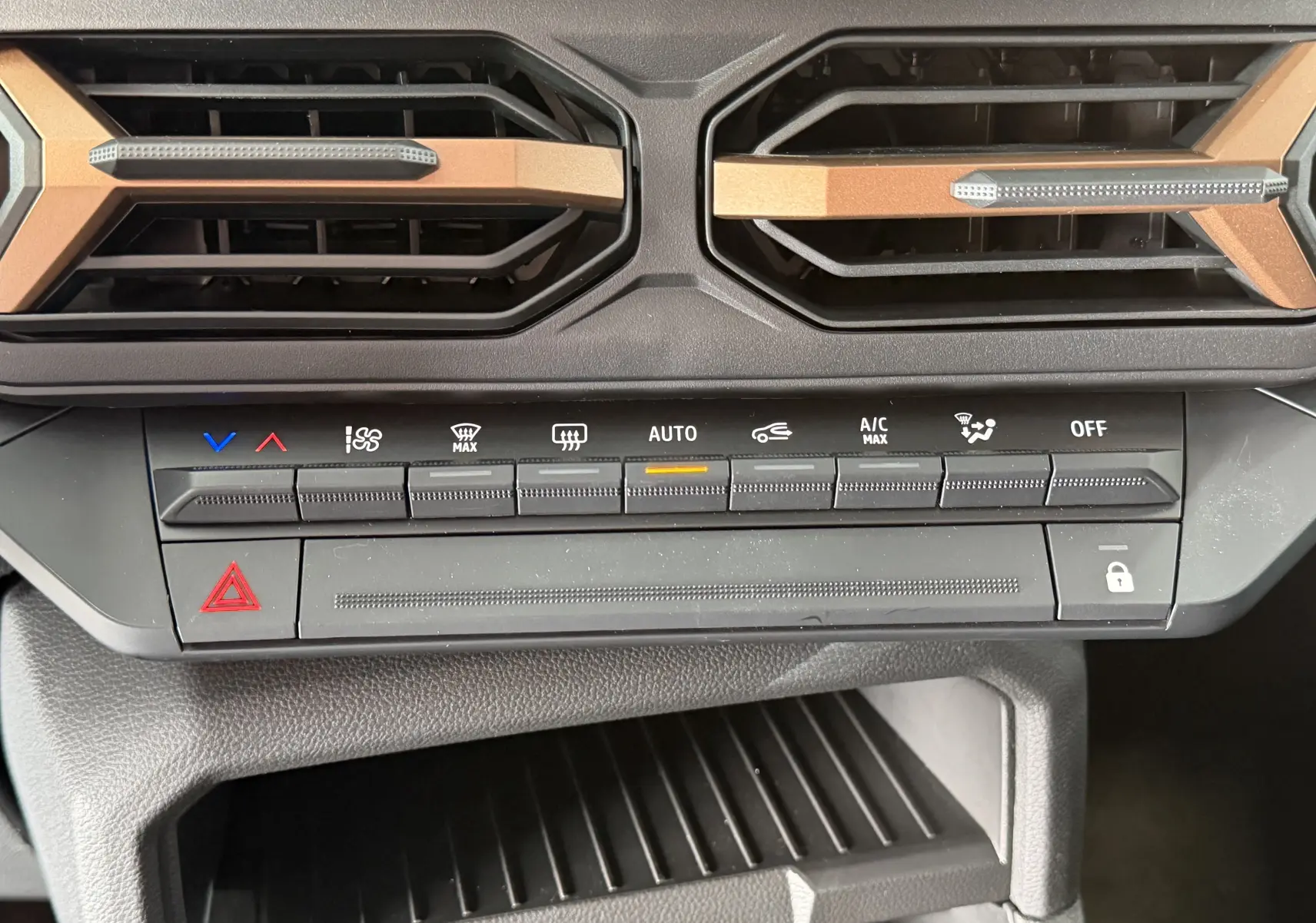 Gros plan sur les commandes de climatisation et les aérateurs noirs avec inserts brun cuivré du Dacia Duster Hybrid 155 Extreme.