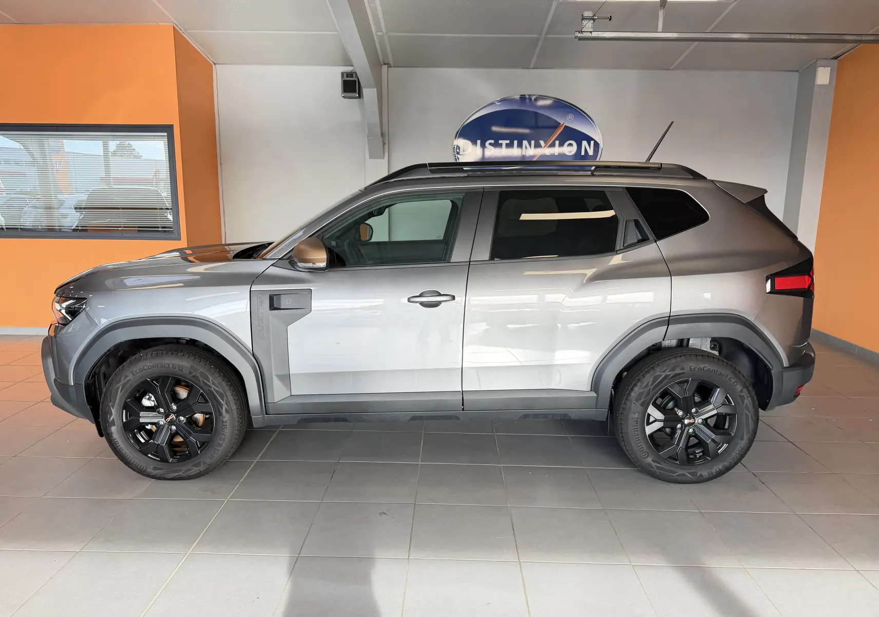 Profil droit du Dacia Duster Hybrid 155 Extreme gris schiste avec jantes noires et coques de rétroviseurs brun cuivré.