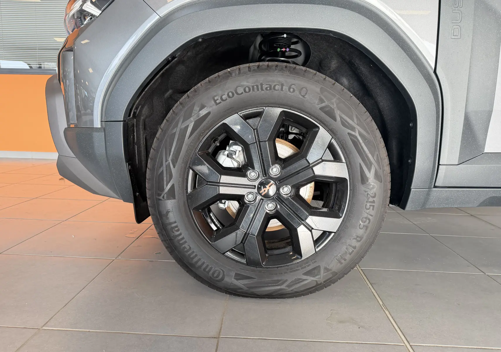 Gros plan sur la roue avant gauche du Dacia Duster Hybrid 155 Extreme gris schiste avec jante alliage 17'' Tergan noire.