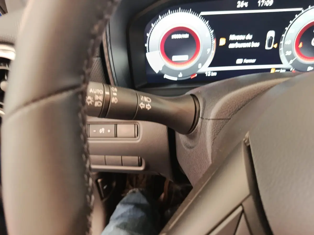 Vue rapprochée du tableau de bord et du volant noir du Nissan Juke 2025, affichage numérique et commandes au volant visibles.