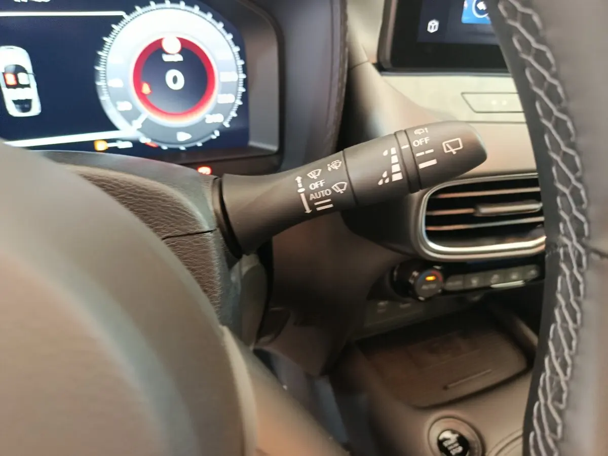Gros plan sur la manette d’essuie-glace à gauche du volant dans l’habitacle du Nissan Juke bleu 2025.