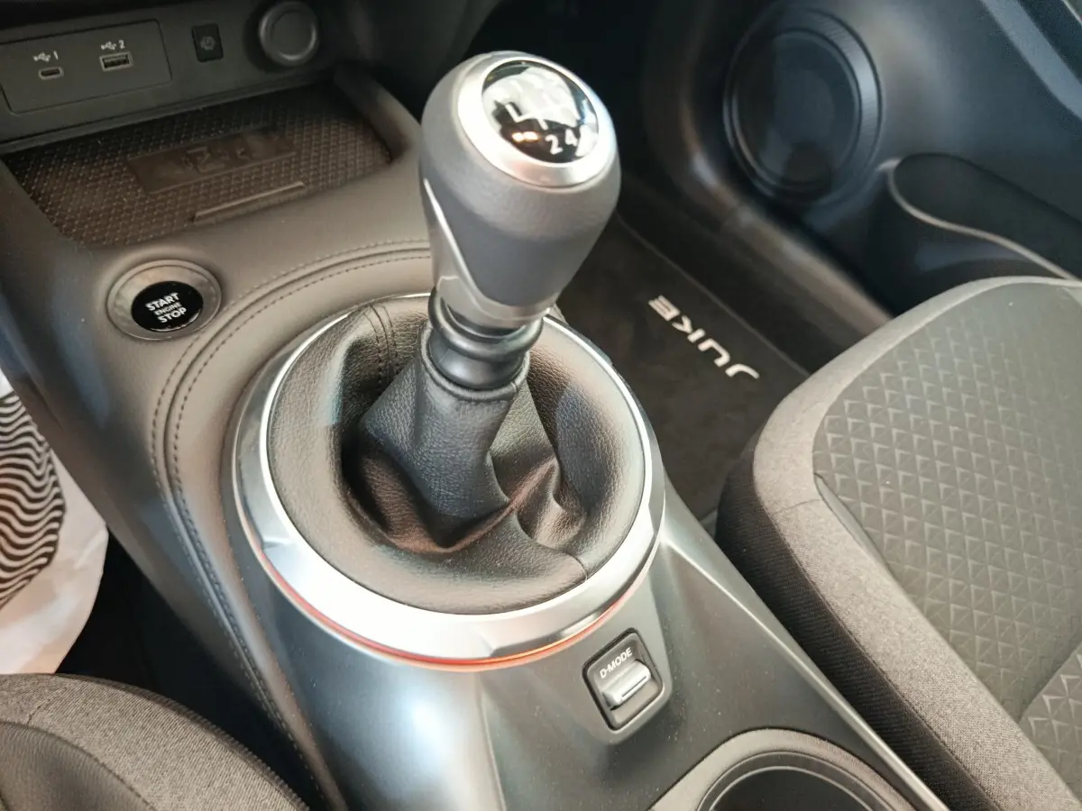 Vue rapprochée de la console centrale intérieure du Nissan Juke bleu 2025, avec levier de vitesse manuel et bouton Start/Stop.