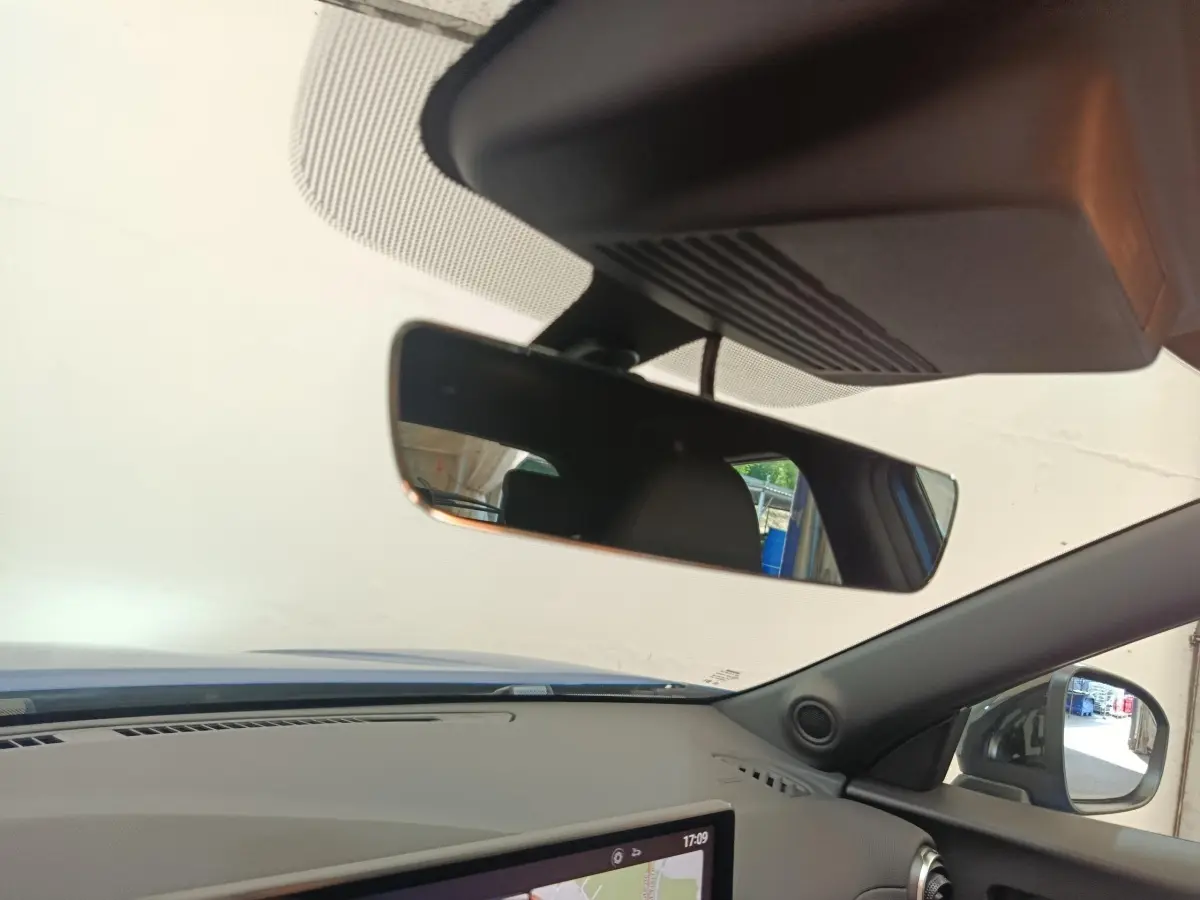 Vue intérieure du tableau de bord et rétroviseur d’un Nissan Juke bleu 2025 avec écran tactile et volant multifonctions.