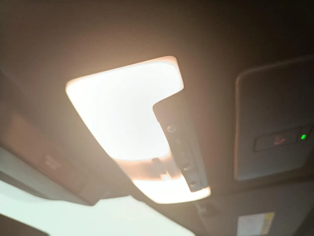 Plafonnier intérieur allumé du Nissan Juke bleu, vue en léger contre-plongée vers l'avant du toit.