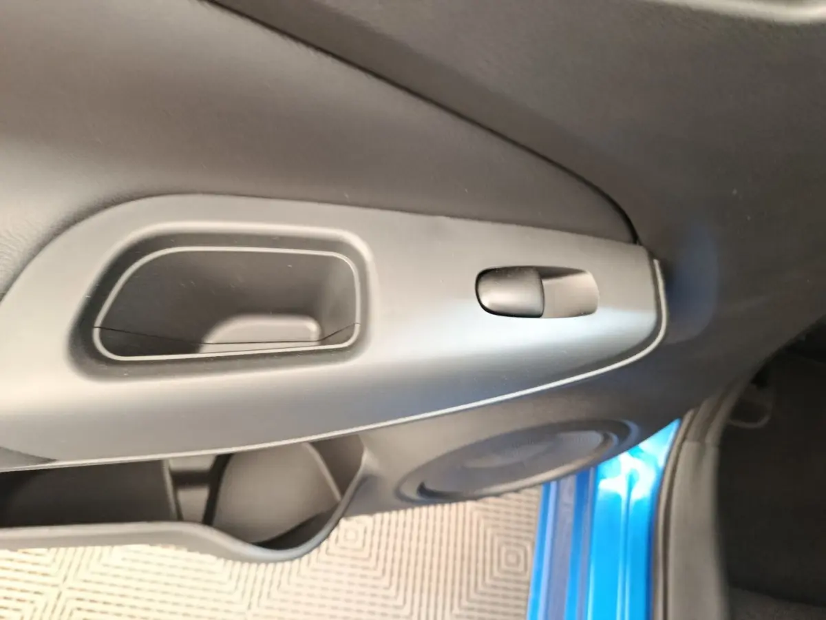 Détail de la poignée intérieure côté gauche avec partie de la porte bleu vif d’un Nissan Juke 2025.