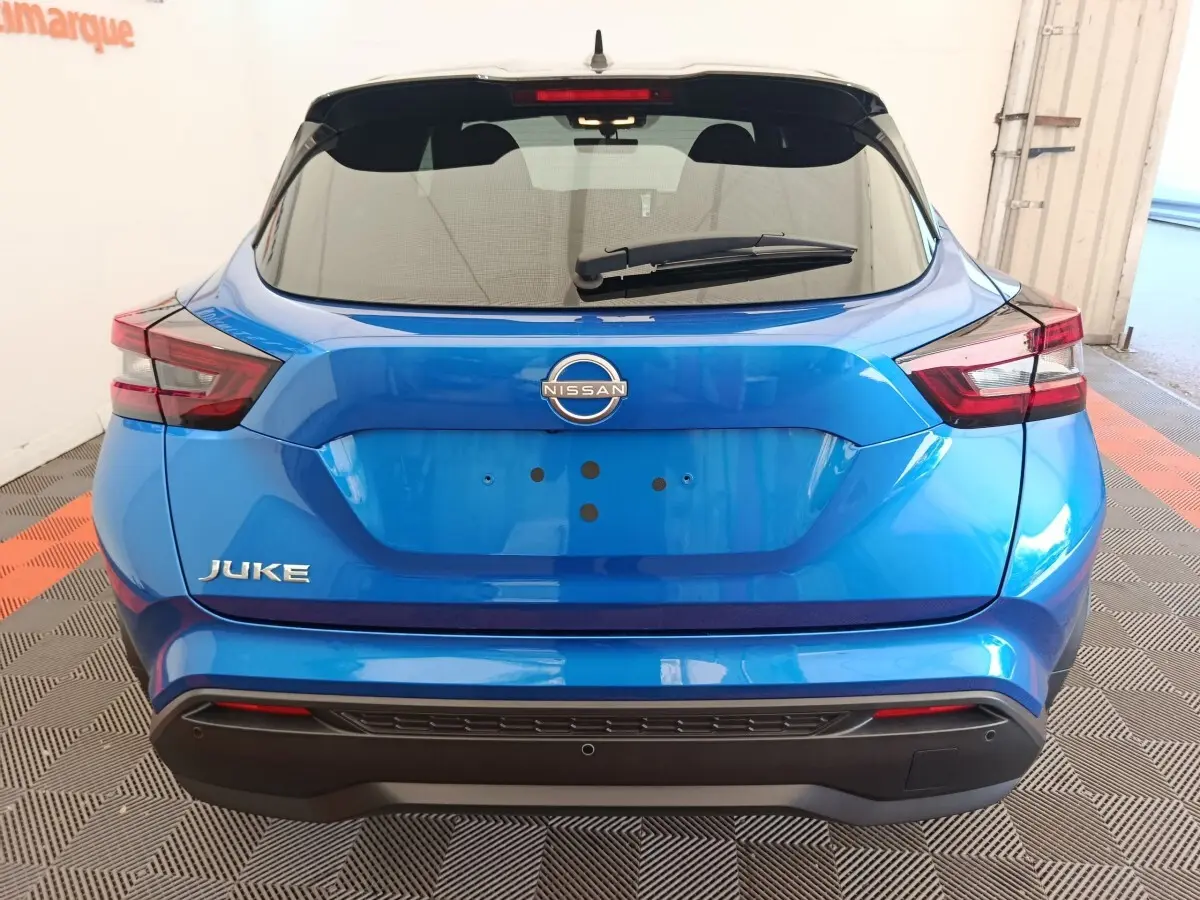 Vue arrière d'un Nissan Juke bleu 2025 avec feux LED et hayon noir brillant dans un garage.