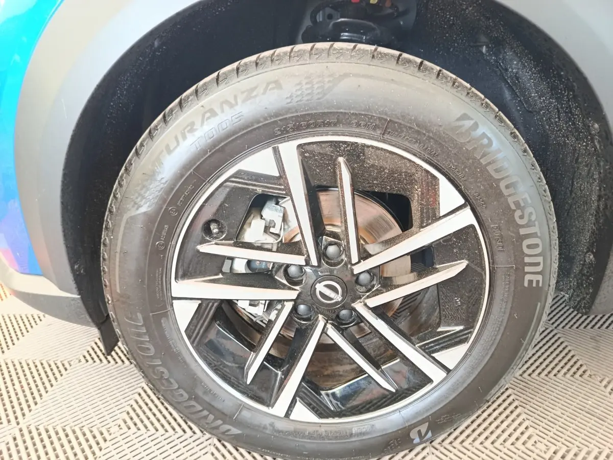 Gros plan sur la roue avant droite du Nissan Juke bleu 2025 avec jante alliage noire et argentée, pneu Bridgestone.