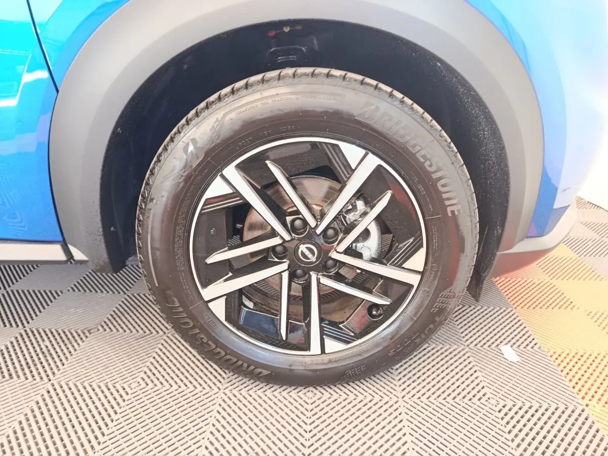Gros plan sur la roue avant droite du Nissan Juke bleu 2025 avec jante alliage noire et argentée.