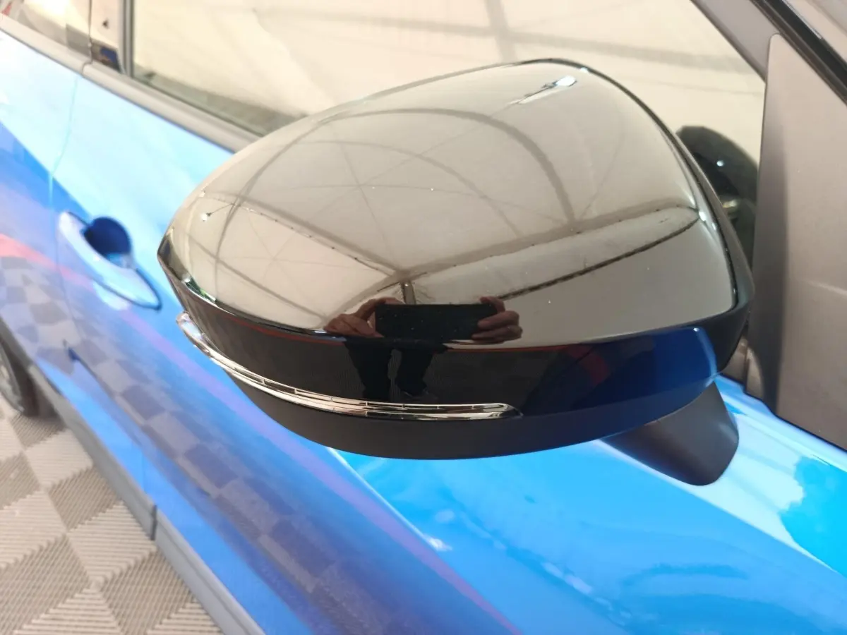 Gros plan sur le rétroviseur droit noir avec clignotant intégré du Nissan Juke bleu 2025 côté conducteur.